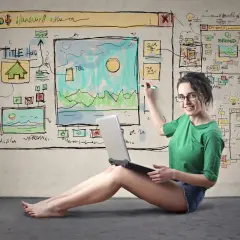 Kobieta z laptopem tworzy szkic strony internetowej, pokazując, że **svg co to** jest format grafiki wektorowej, idealny do projektów online.