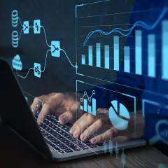 Ręce na klawiaturze laptopa, nad nimi wizualizacje danych i schematy. To pokazuje, jak działa machine learning.