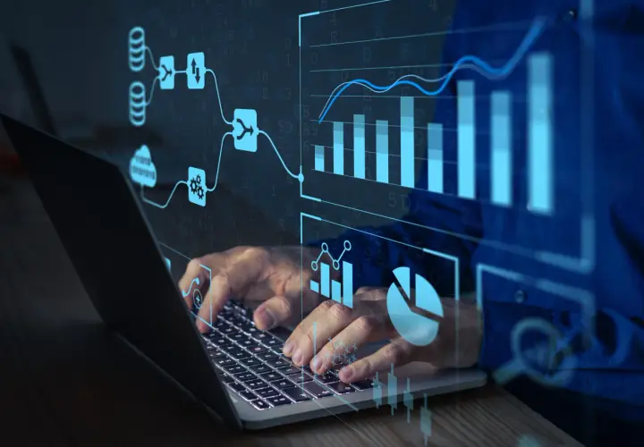 Ręce na klawiaturze laptopa, nad nimi wizualizacje danych i schematy. To pokazuje, jak działa machine learning.