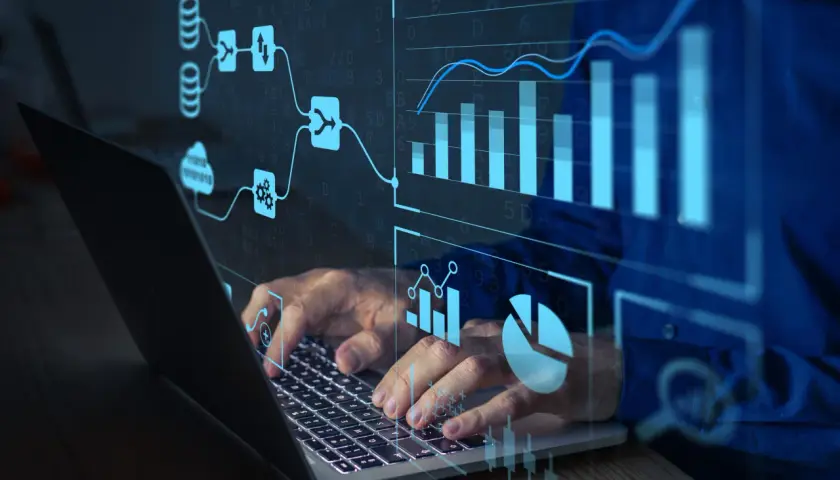 Ręce na klawiaturze laptopa, nad nimi wizualizacje danych i schematy. To pokazuje, jak działa machine learning.